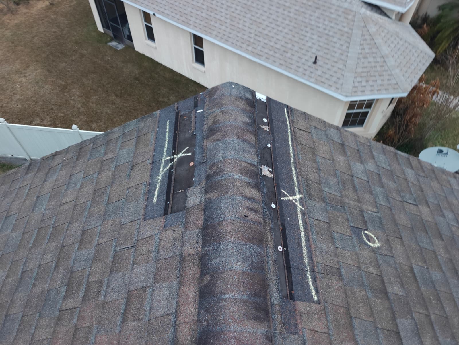 Aerial view of ridge cap shingles chalk-marked for storm damage in Central Florida