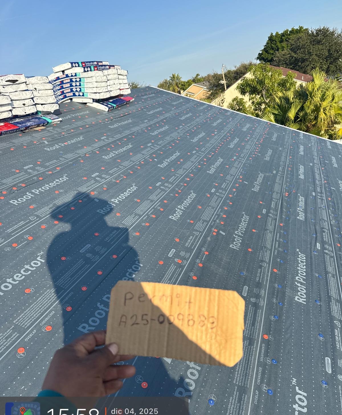 Fresh underlayment installed with new architectural shingles staged on the ridge