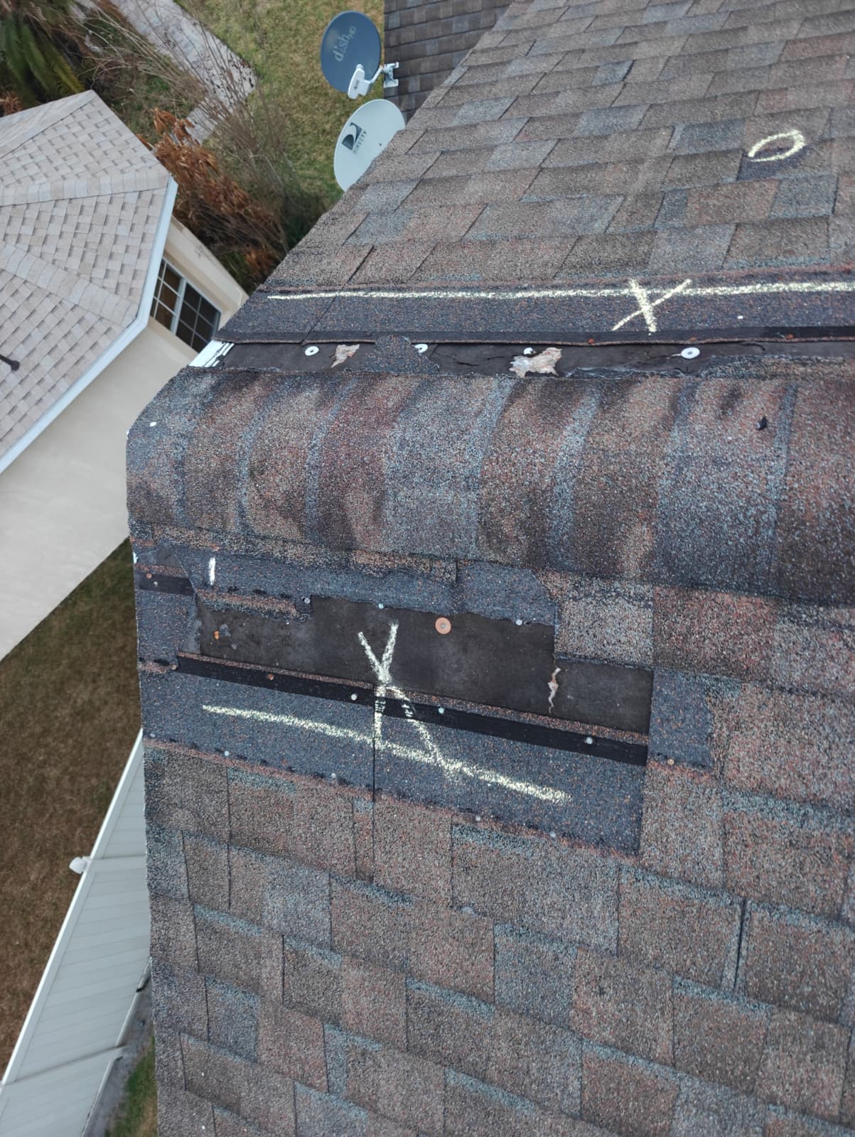 Storm-damaged hip with lifted shingles and exposed decking